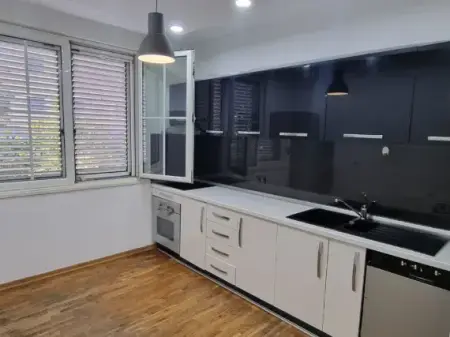 Sheshi Wilson, buzë rrugës, prane  Postës Nr. 8, në katin e 3-të të një pallati ekzistues.
